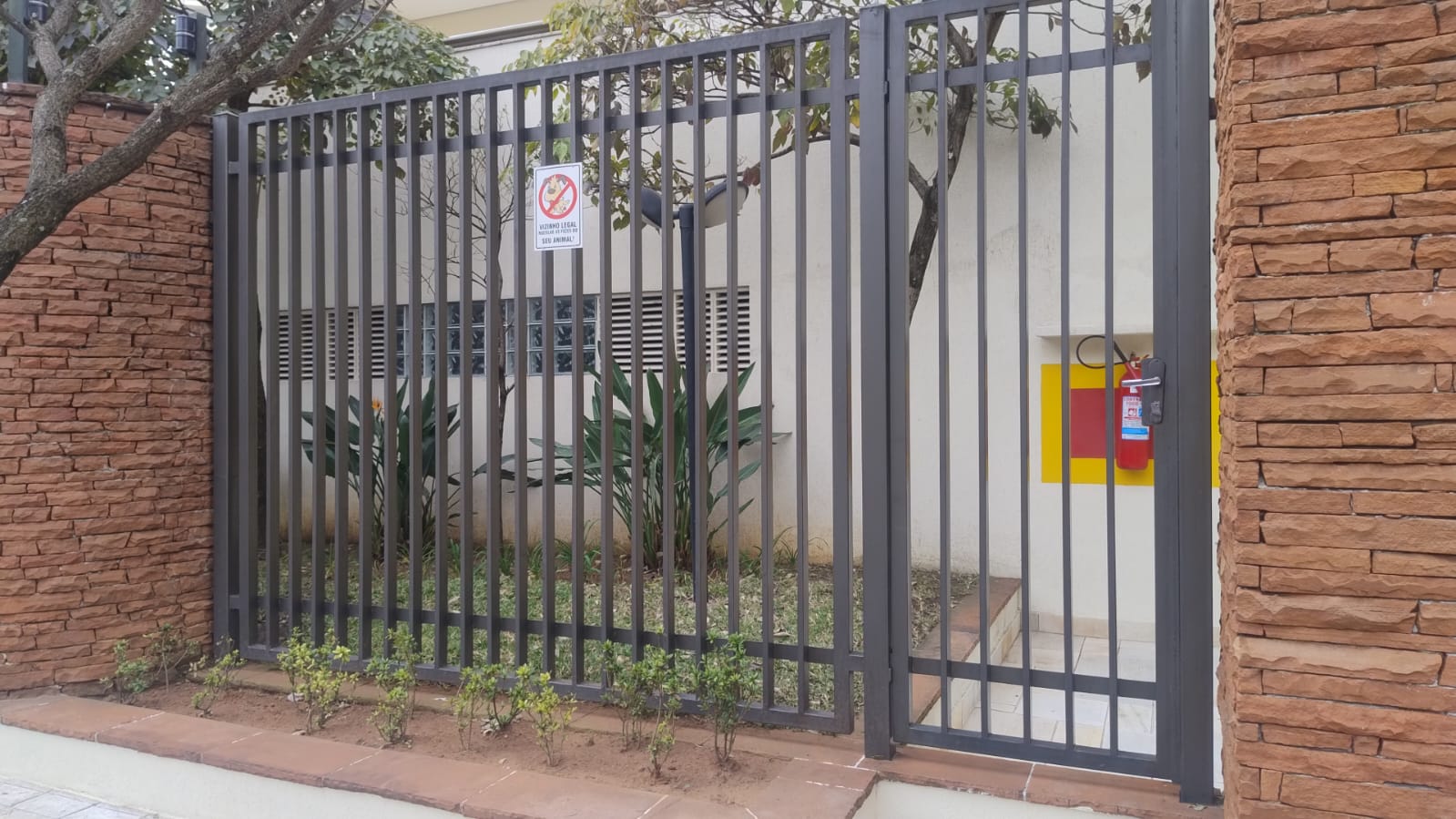 Portão social e grade metálica sob medida instalados em muro de pedra